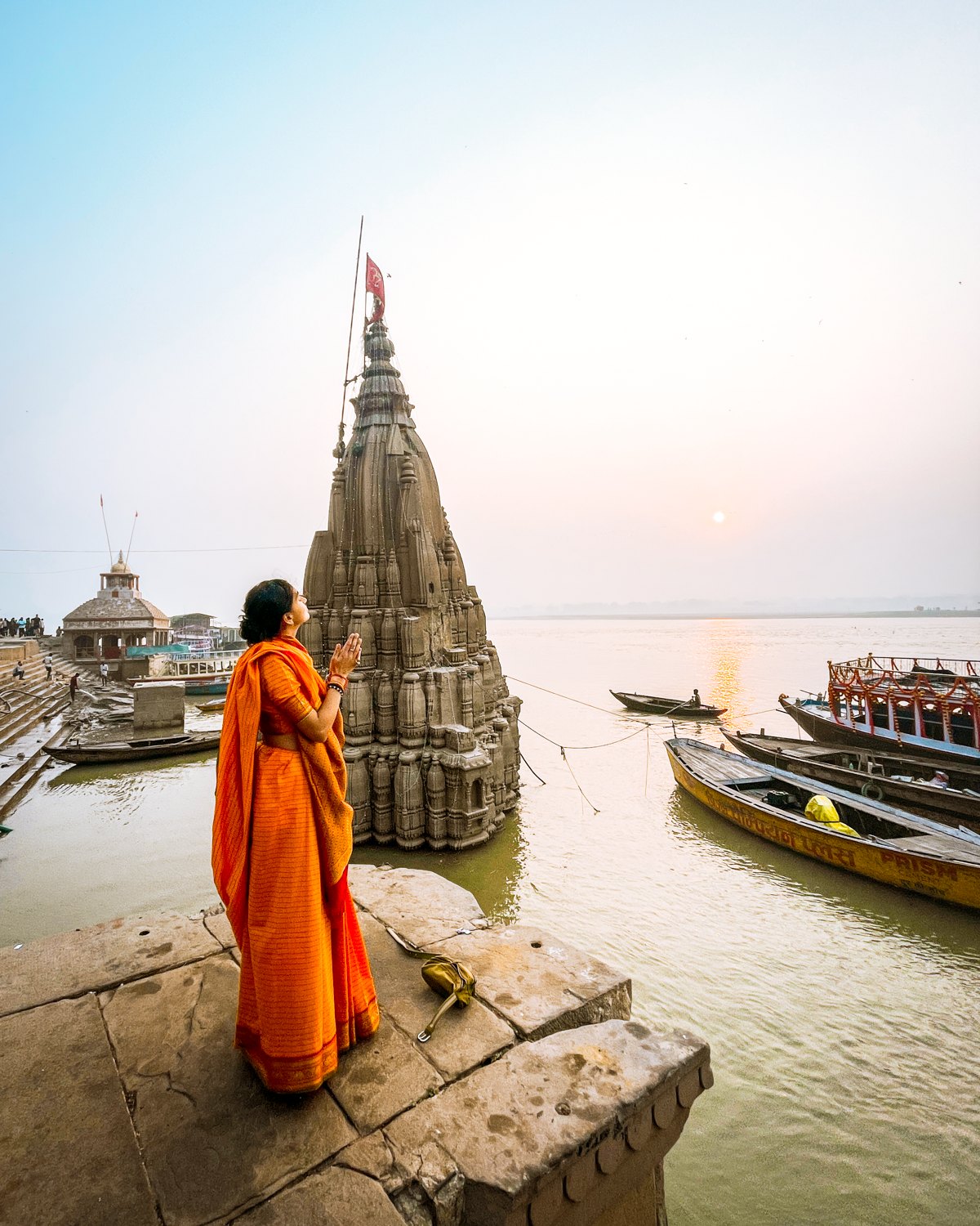Kamya in prayer before the leaning Ratneshwar temple on the Ganga