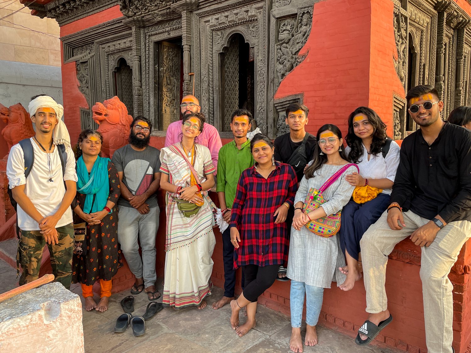The circle outside a carved temple, wearing tilak